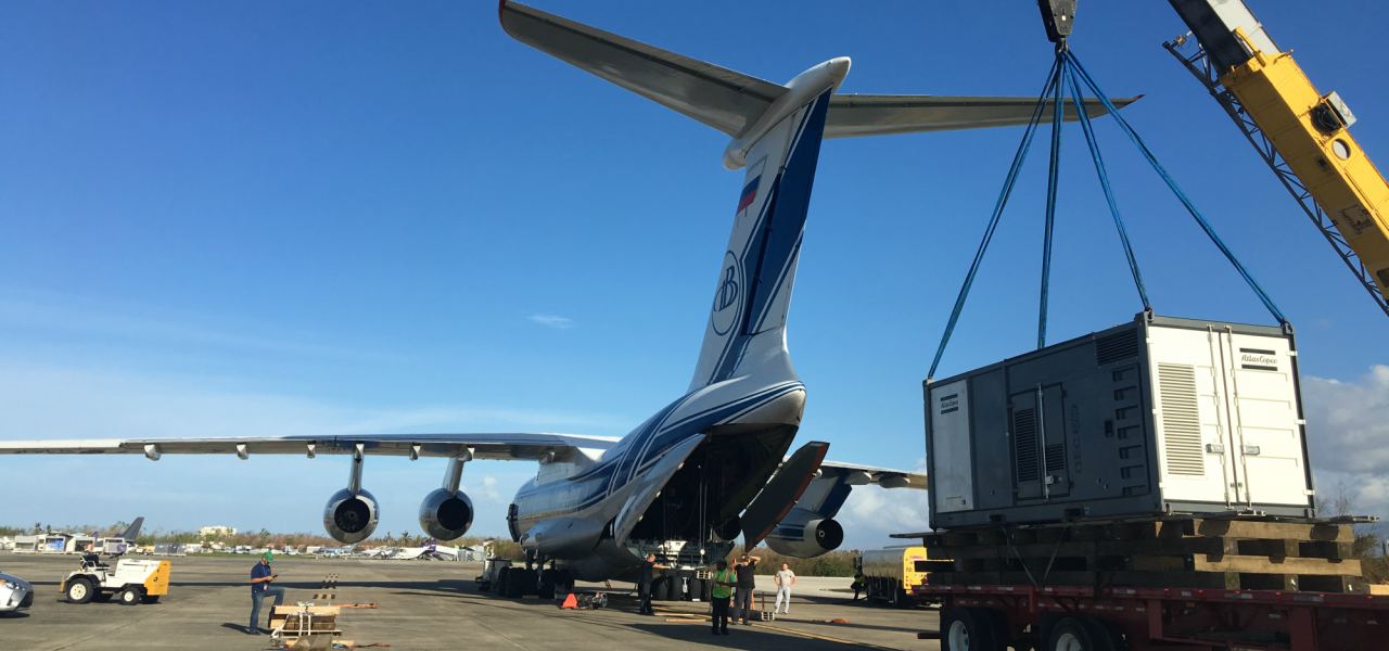 A flatbed truck on a runway gets ready to load an electrical transformer onto an Ilyushin-76, bound for Puerto Rico