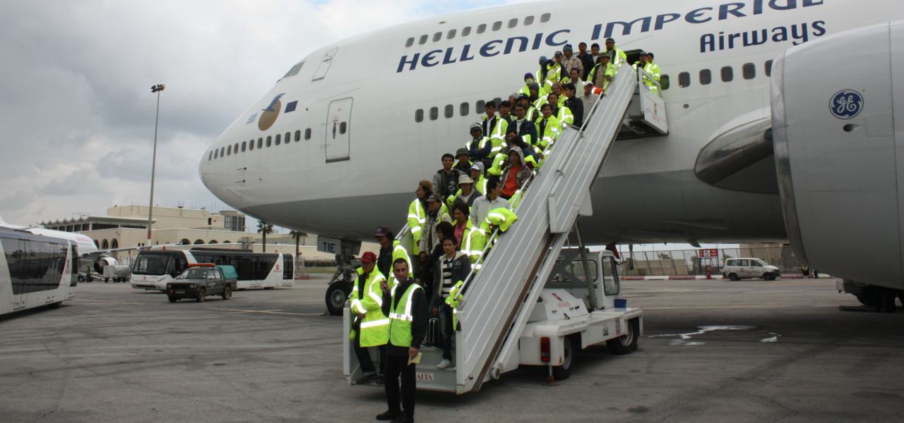 Airline personnel stand on a stairway leading up to a passenger jet